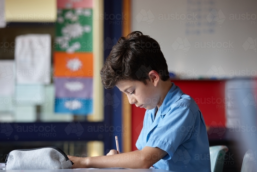 Primary school student in classroom working on homework - Australian Stock Image