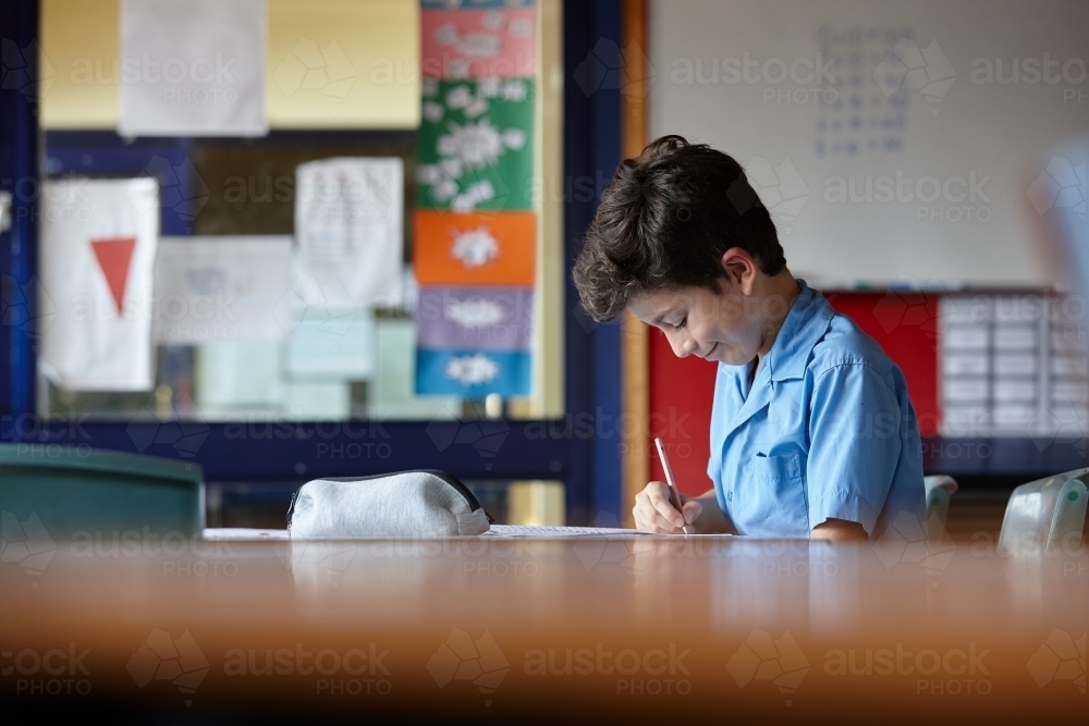 Primary school student in classroom working on homework - Australian Stock Image