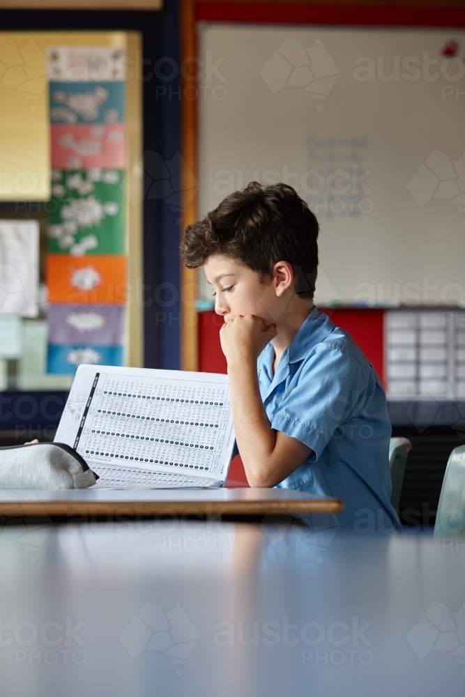 Primary school student in classroom working on homework - Australian Stock Image