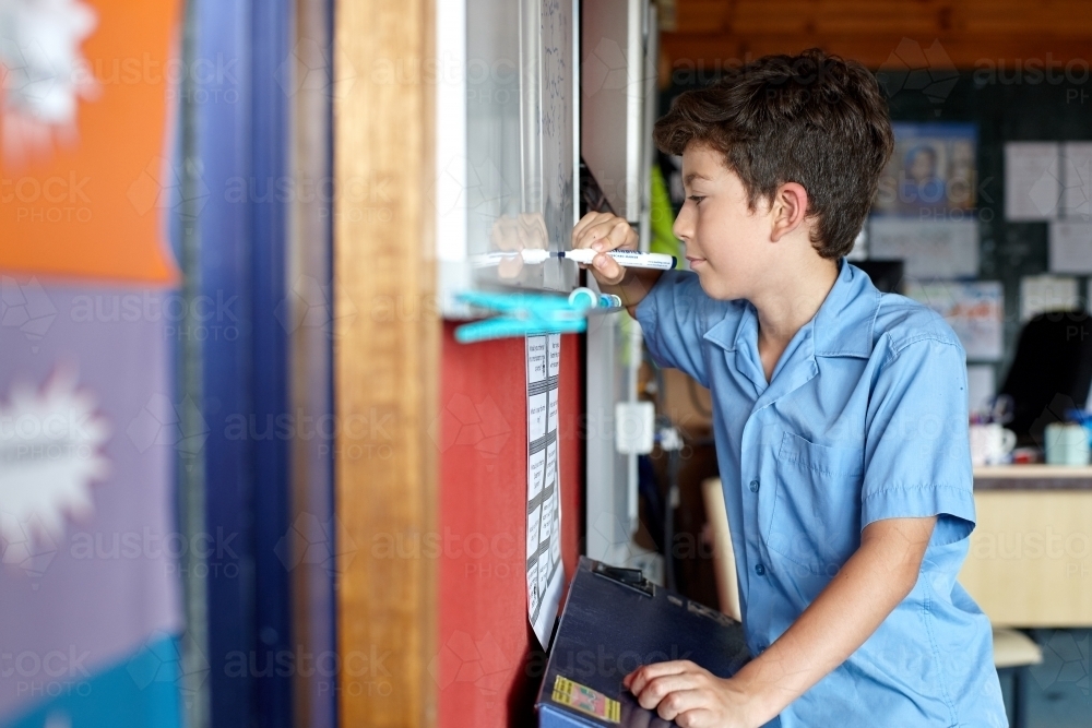Primary school student writing on whiteboard - Australian Stock Image