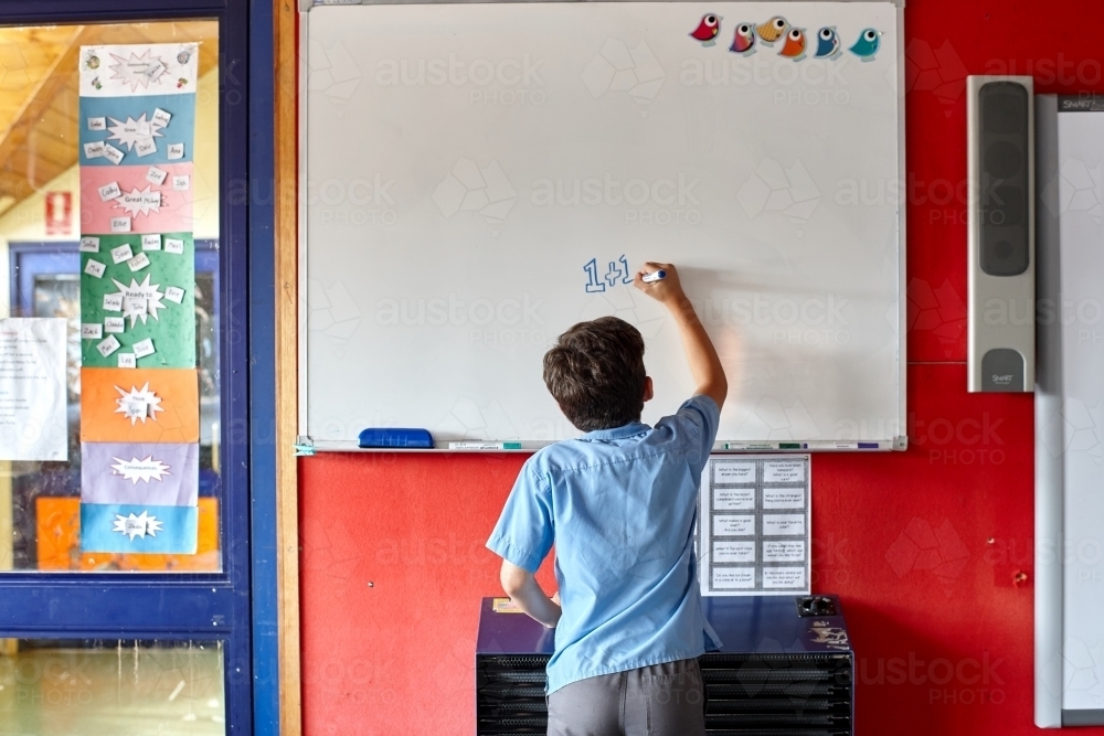 Primary school student writing on whiteboard - Australian Stock Image