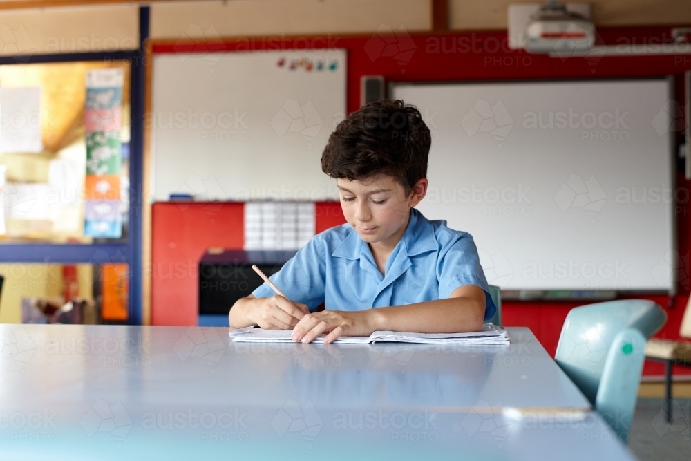 Primary school student in classroom working on homework - Australian Stock Image