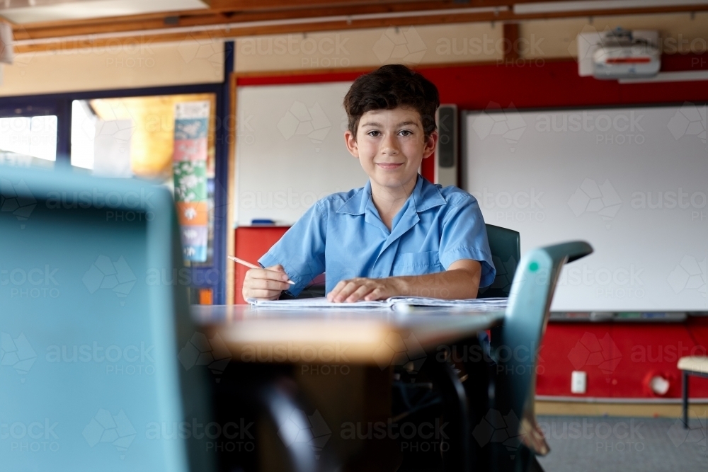 Primary school student in classroom working on homework - Australian Stock Image