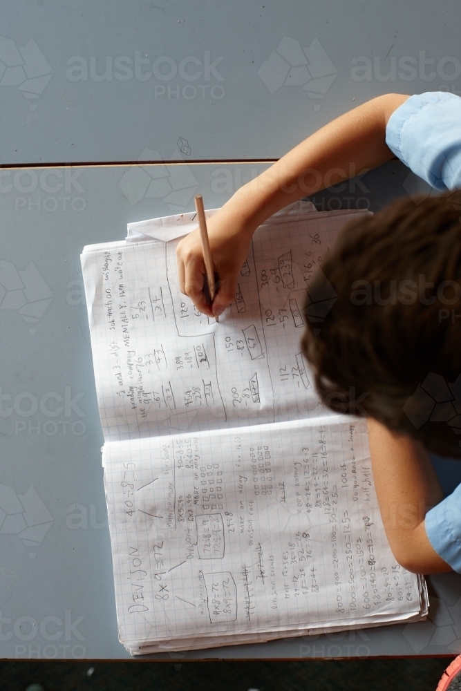 Primary school student in classroom working on homework - Australian Stock Image