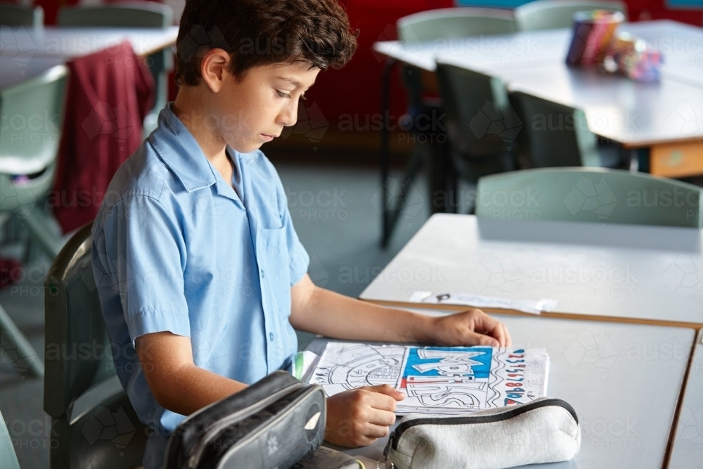 Primary school student in classroom working on maths homework - Australian Stock Image