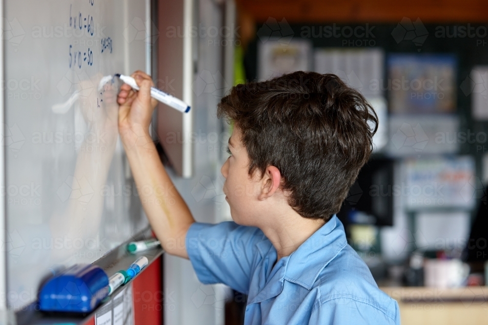 Primary school student in classroom writing on whiteboard : Austockphoto Primary school student in classroom writing on whiteboard - Australian Stock Image