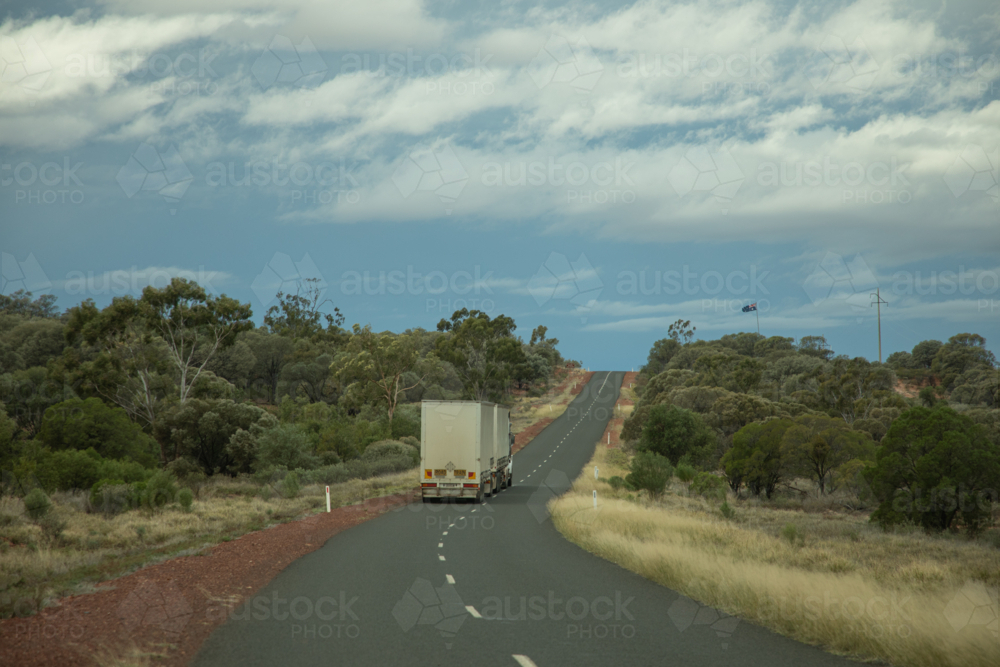Prime mover pulling two curtain sided trailers going up a jump-up - Australian Stock Image