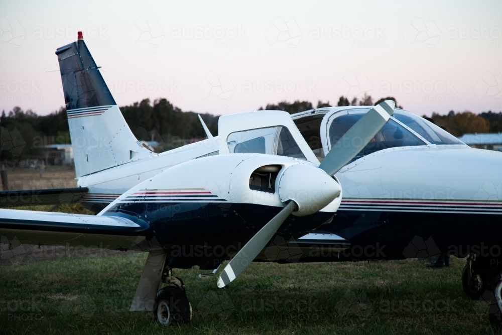 Private twin engine aeroplane on rural landing strip at dusk - Australian Stock Image
