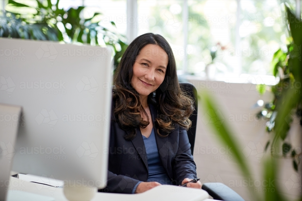 Professional business woman sitting at a desk with a computer - Australian Stock Image