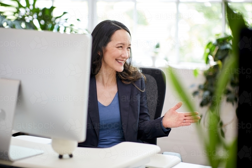 Professional business woman sitting at a desk with computer - Australian Stock Image