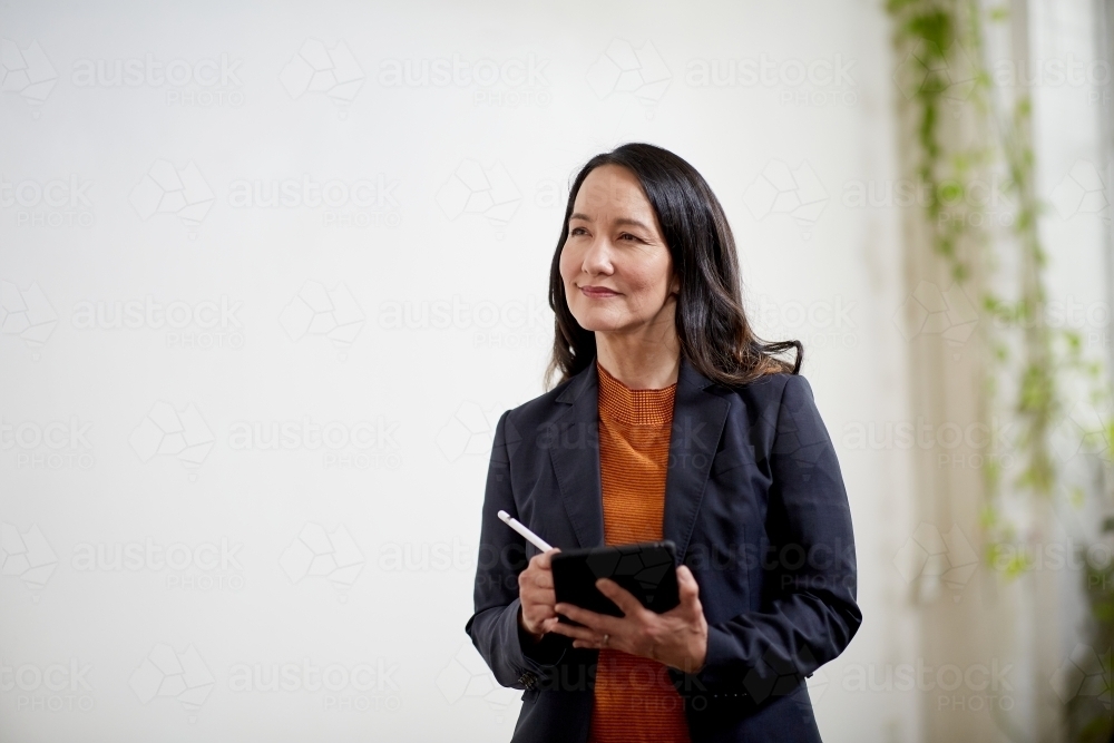 Professional business woman standing, thinking in an open studio - Australian Stock Image
