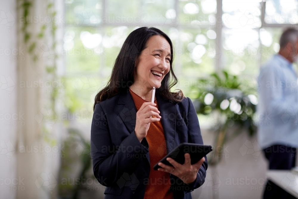 Professional business woman standing, thinking in an open studio - Australian Stock Image