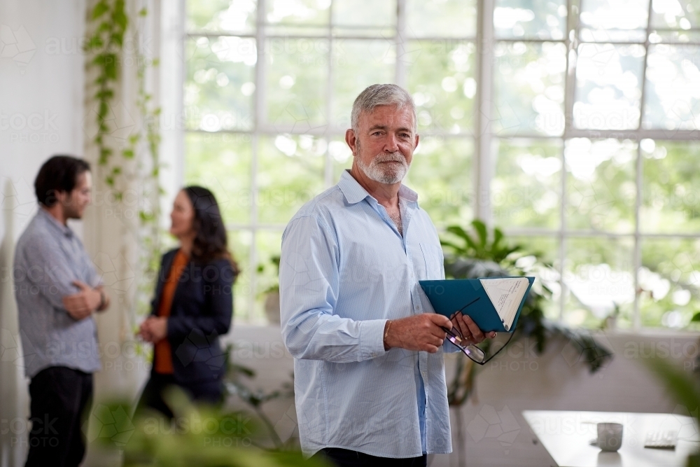 Professional businessman standing in an open studio office - Australian Stock Image