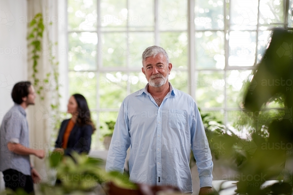 Professional businessman standing, thinking in an open plan office studio - Australian Stock Image