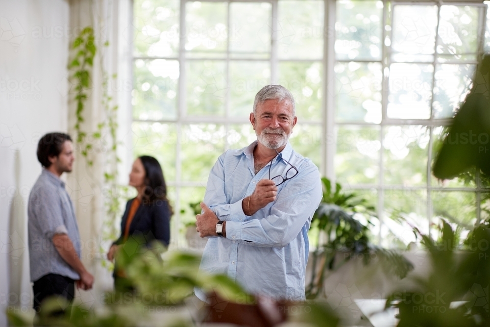 Professional businessman standing, thinking in an open plan office studio - Australian Stock Image