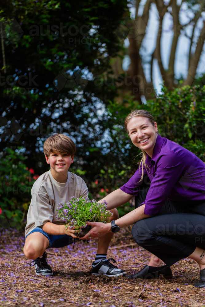 Professional woman and child planting flowers together - growth through therapy concept - Australian Stock Image