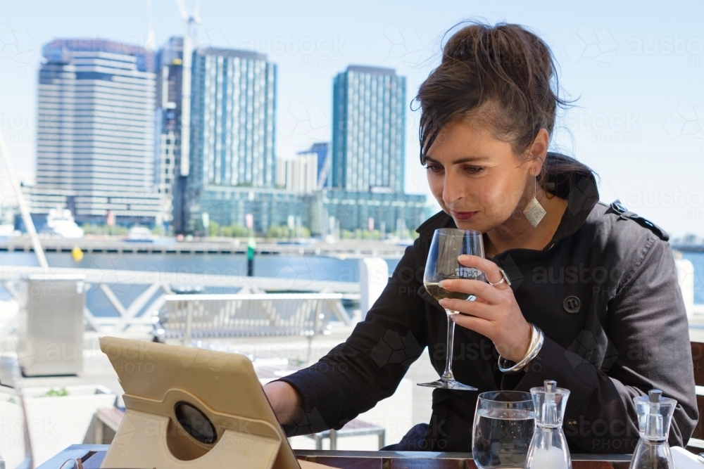 Professional woman working on a tablet over lunch at Docklands in Melbourne - Australian Stock Image
