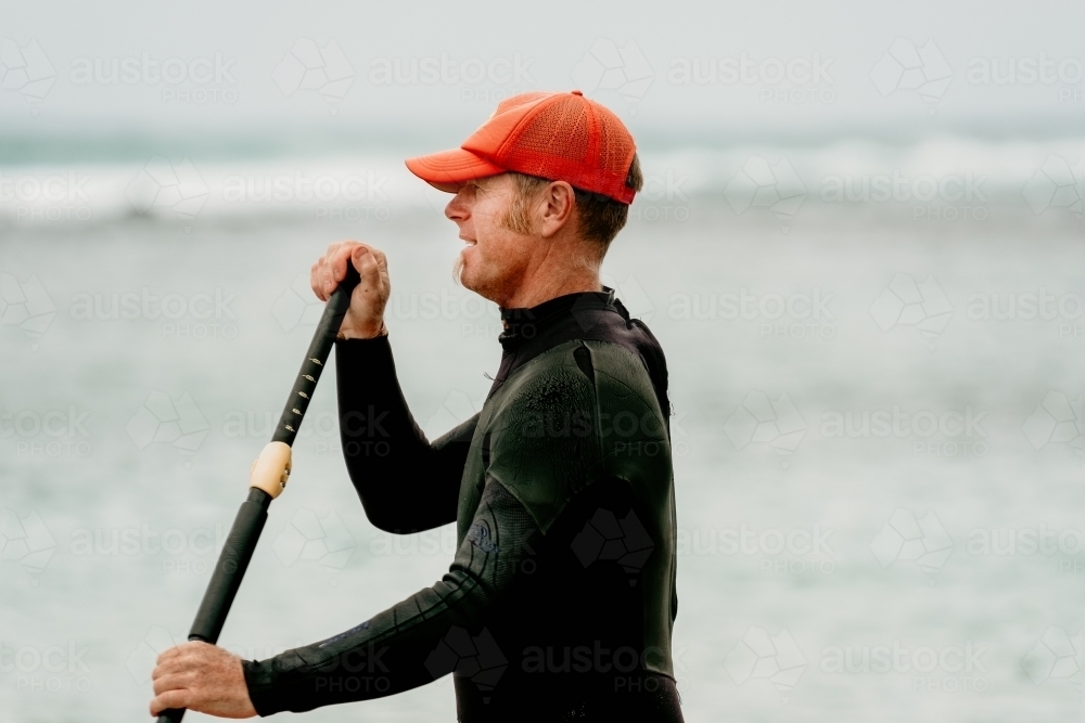 Profile of a man paddle boarding on the ocean - Australian Stock Image