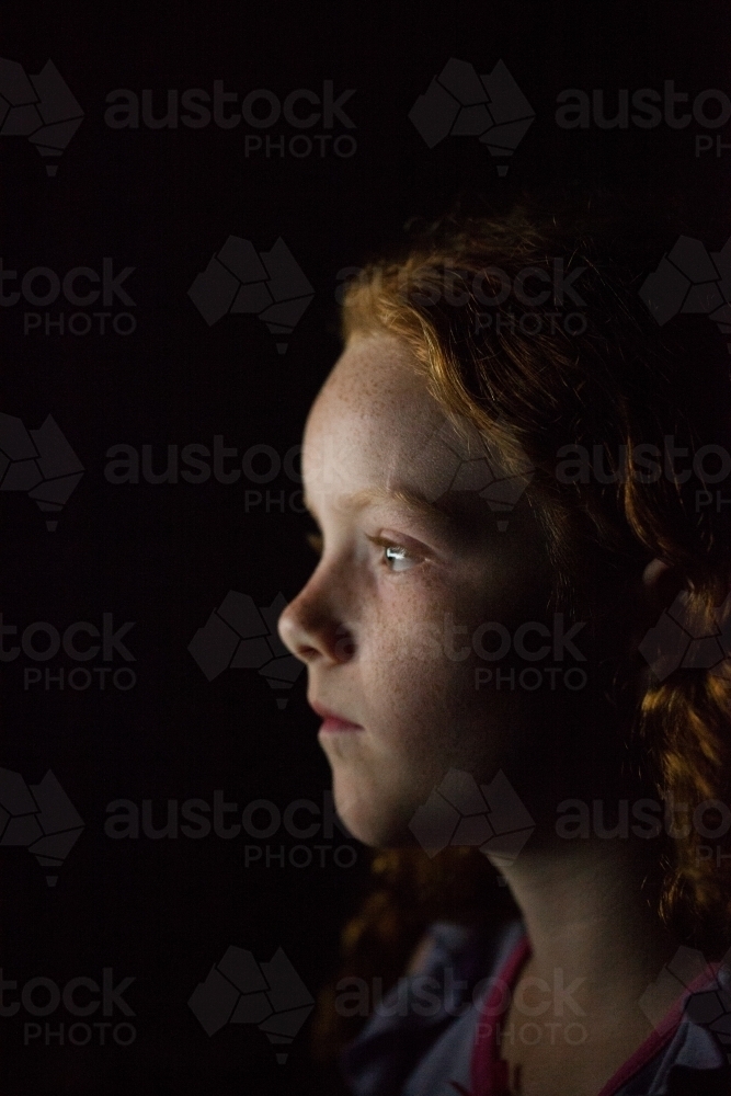Profile of a young girl in low light - Australian Stock Image