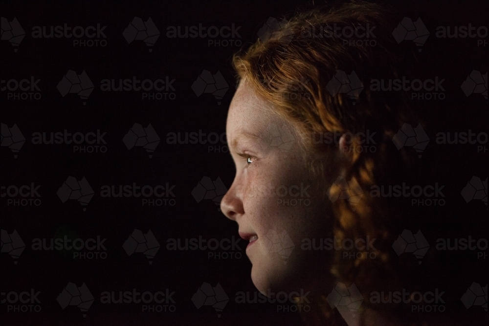 Profile of a young girl in low light - Australian Stock Image