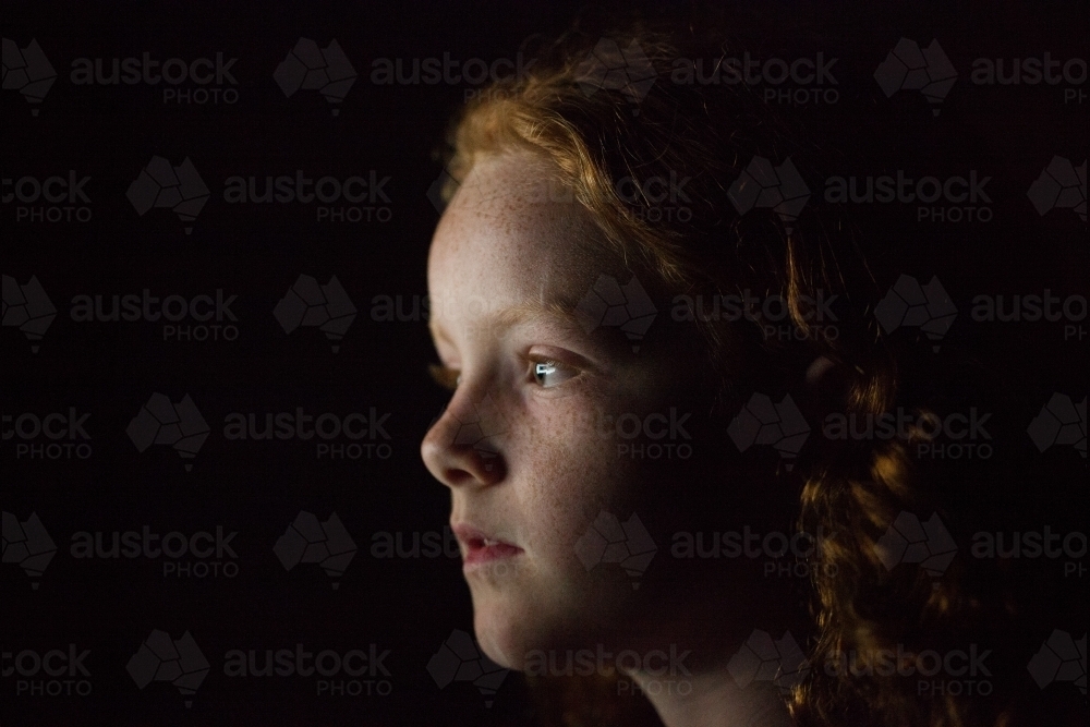 Profile of a young girl in low light - Australian Stock Image