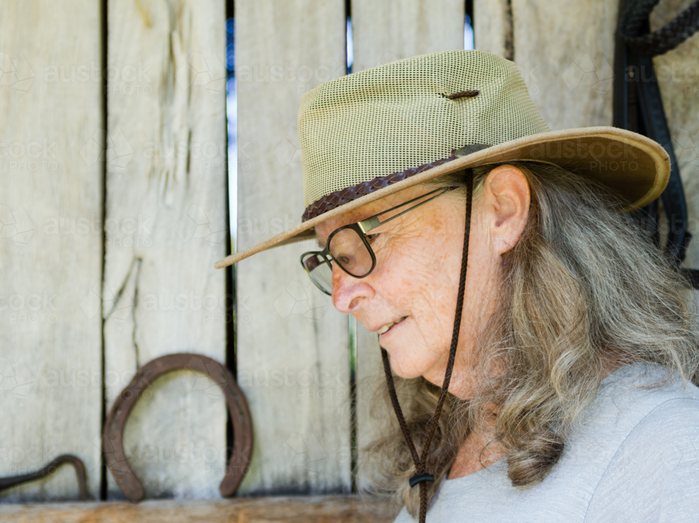 Profile of an older woman with hat and glasses and a horseshoe - Australian Stock Image