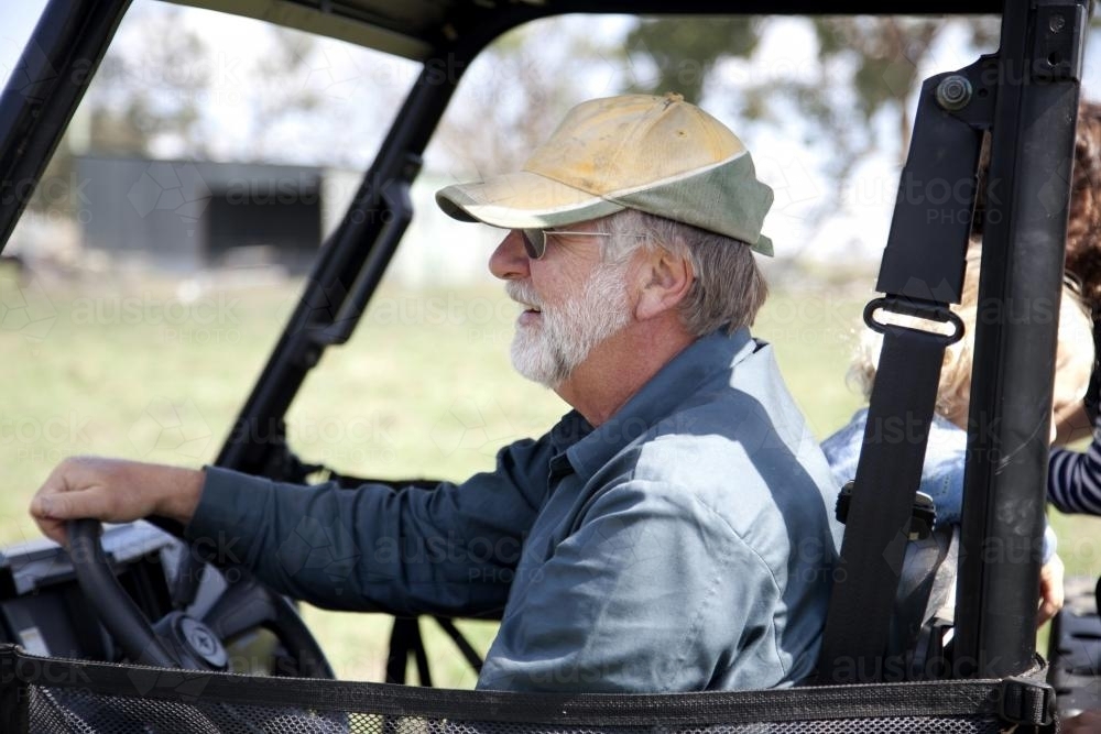 Profile of middle aged male farmer driving on rural property - Australian Stock Image