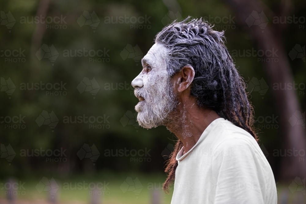 Profile portrait of aboriginal man against a dark bush background - Australian Stock Image