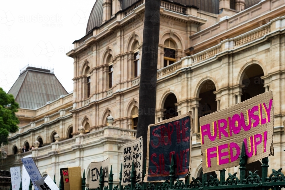 Protest signs on a fence outside a grand old sandstone building - Australian Stock Image