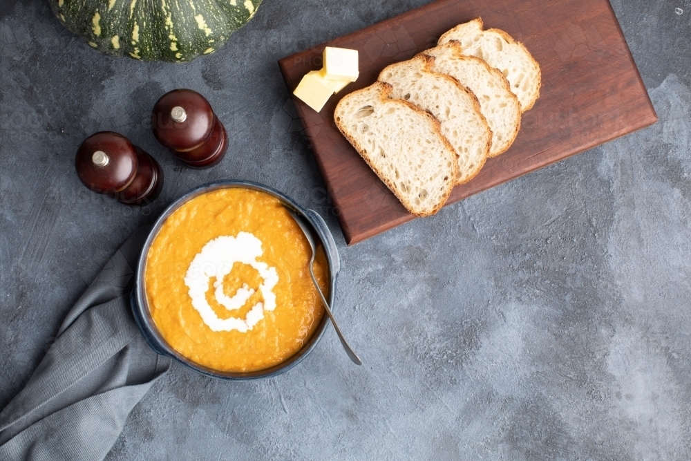 Pumpkin soup scene on dark blue kitchen bench with whole pumpkin - Australian Stock Image
