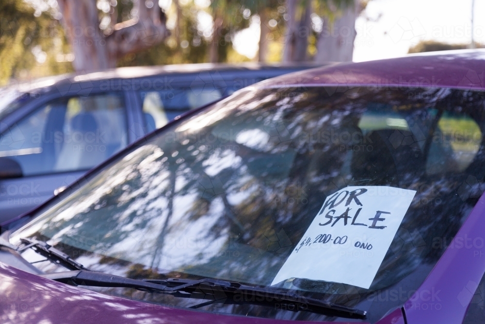 Purple car for sale beside the road with sign in window - Australian Stock Image