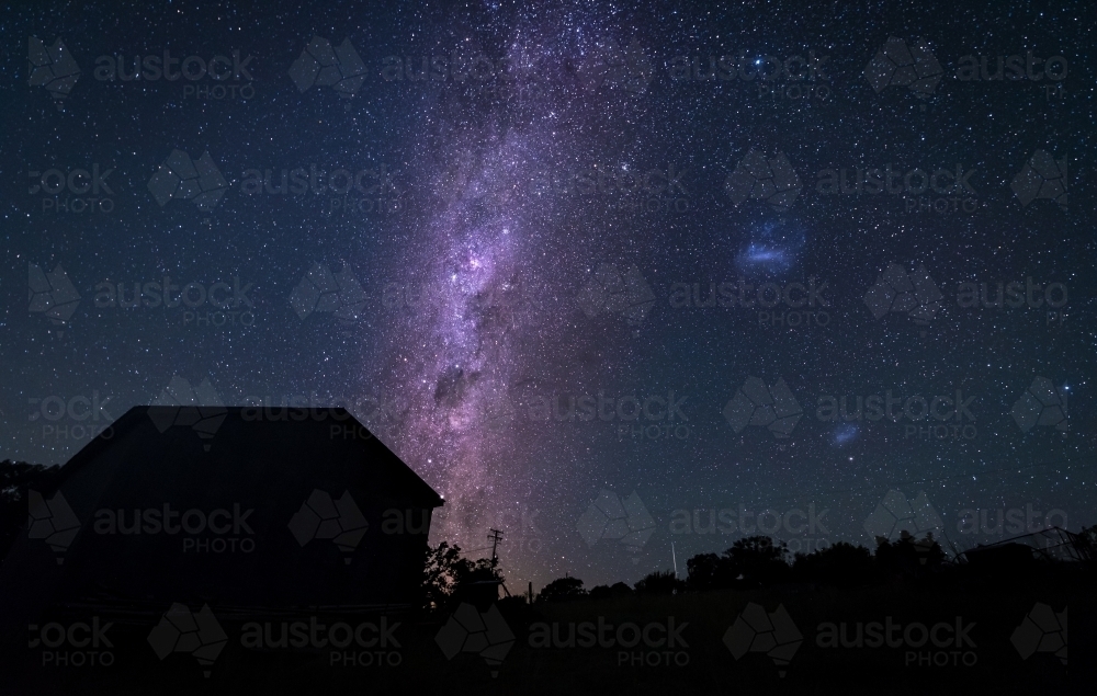 Purple milky way behind silhouetted house - Australian Stock Image