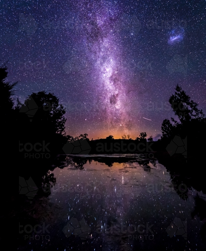 Purple milky way behind still lake - Australian Stock Image