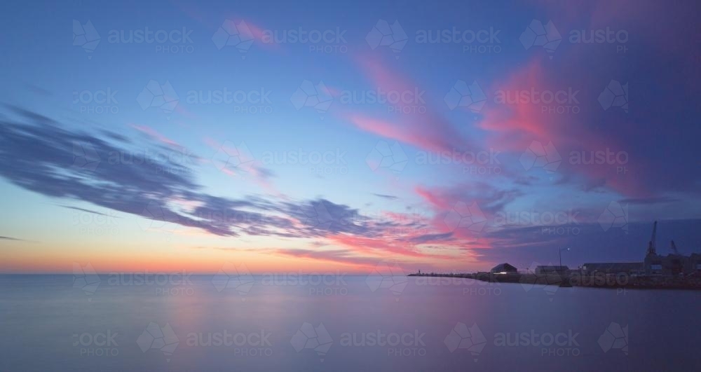 Purple sunset over ocean and point of land - Australian Stock Image