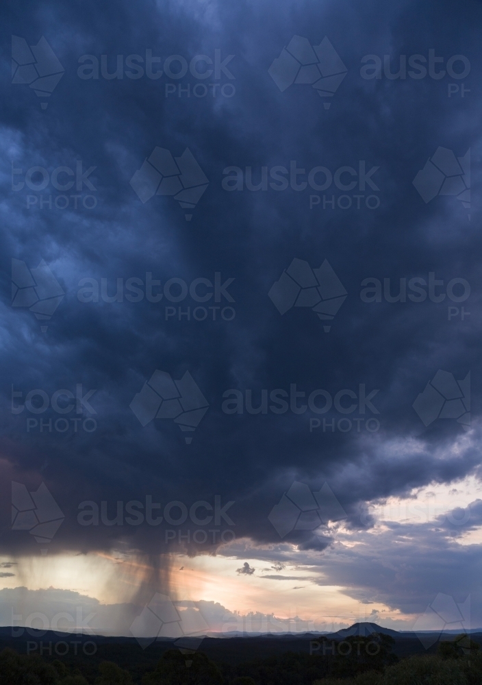 Purple thunderstorm cloud with falling rain and Mount Yengo - Australian Stock Image