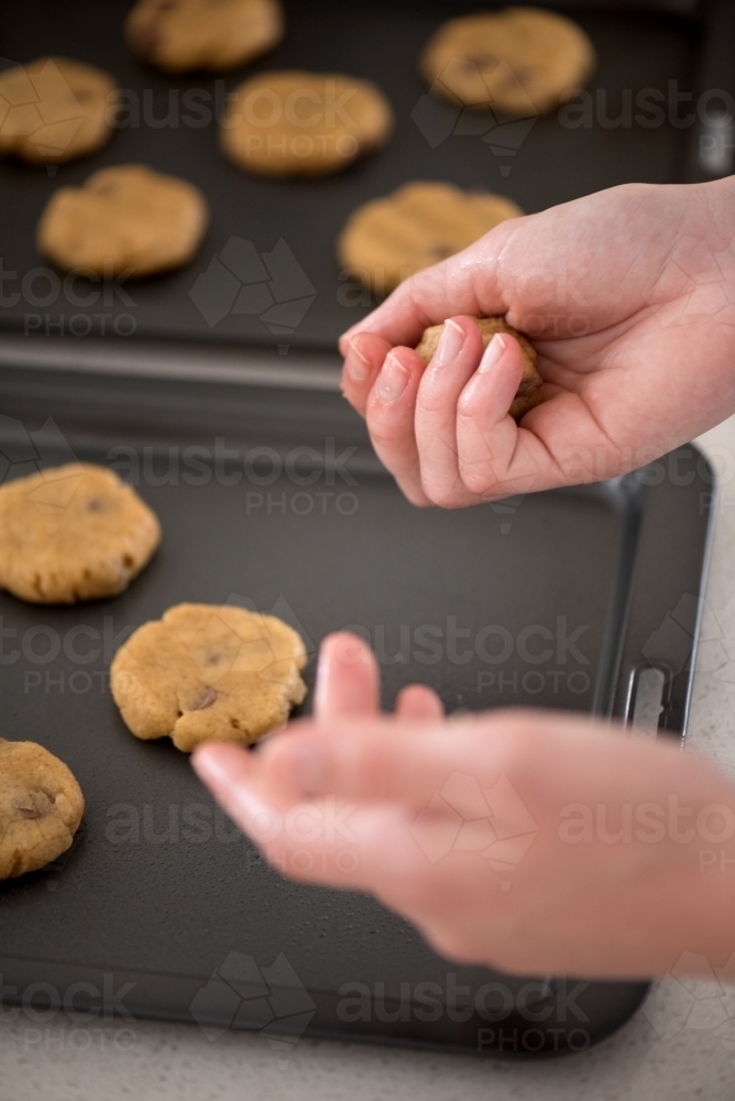 Putting cookie dough onto baking trays - Australian Stock Image