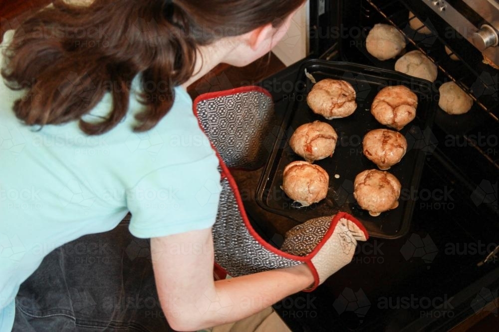 Putting hot cross buns in the oven - Australian Stock Image