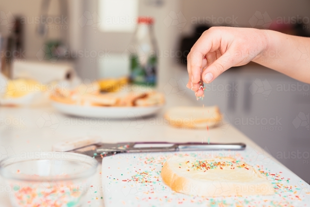 Putting sprinkles on fairy bread - Australian Stock Image