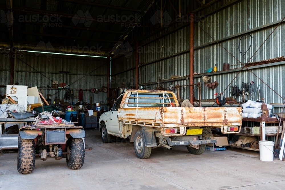 quad bike and farm ute parked in farm shed - Australian Stock Image