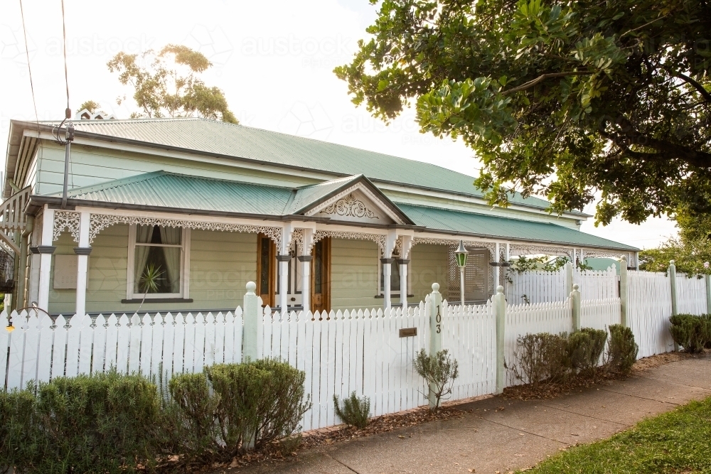 Queenslander house with a front verandah behind a white picket fence - Australian Stock Image