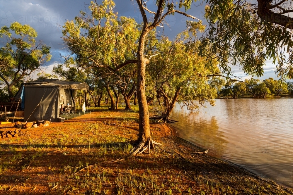 Quiet campsite by an outback lagoon in early morning golden light - Australian Stock Image