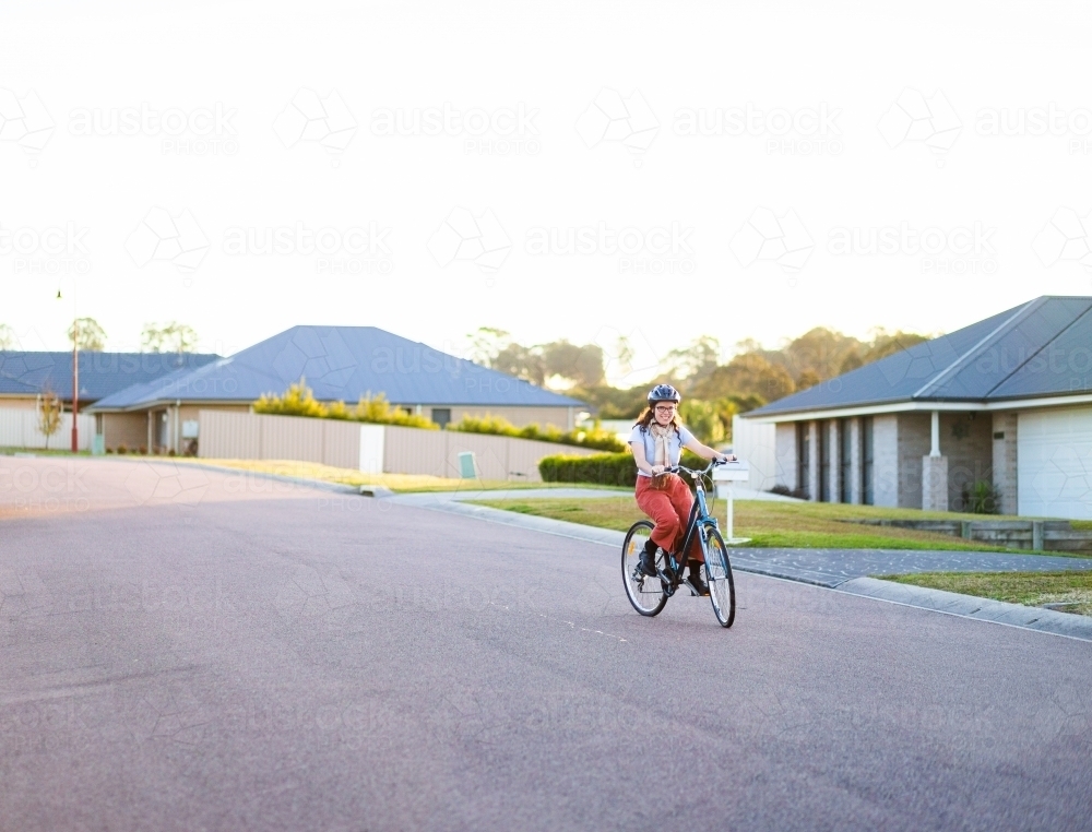 Quiet street in housing area of town with female riding bike for exercise - Australian Stock Image