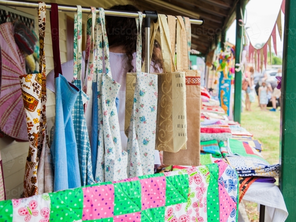 Quilted items and kitchen aprons for sale at a market stall - Australian Stock Image