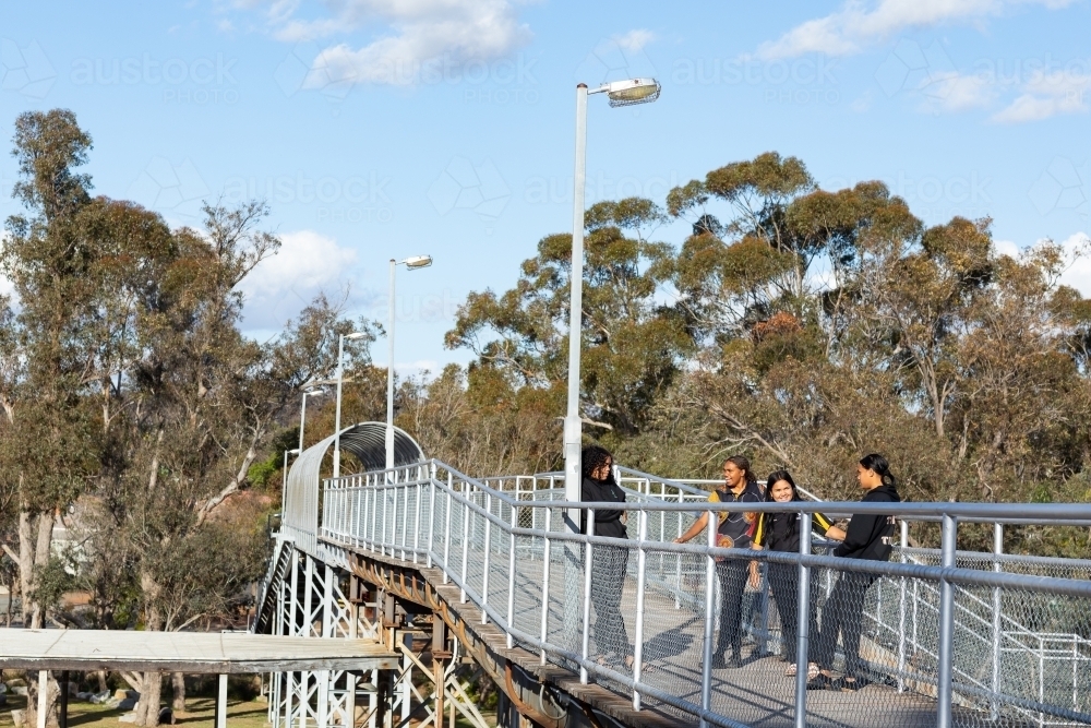 railway bridge with trees and four teenagers - Australian Stock Image