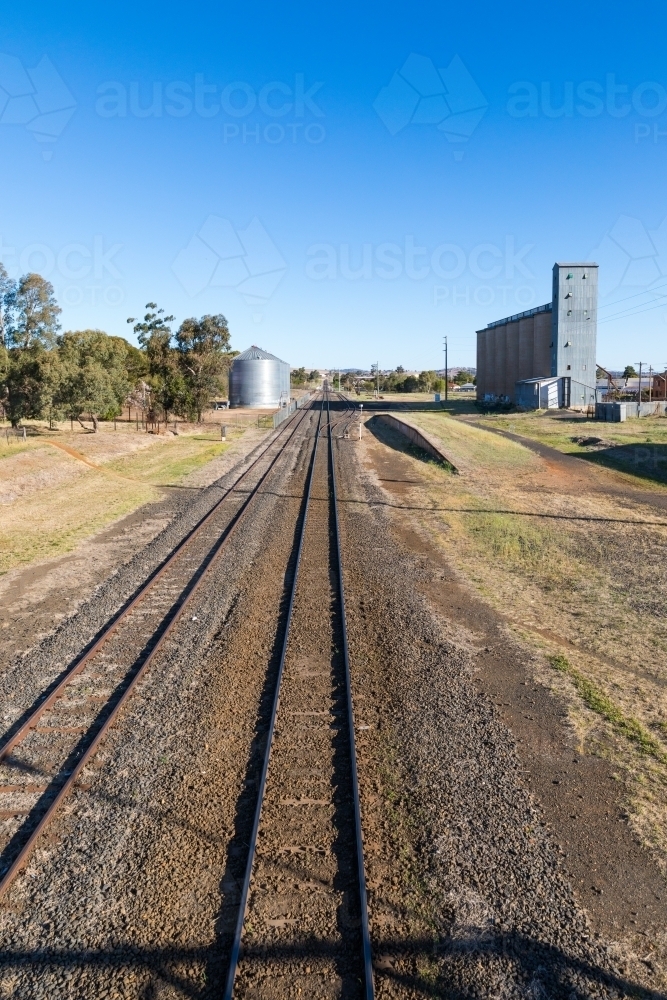 Railway lines leading up to industrial area with rail siding, platform and factory silos - Australian Stock Image