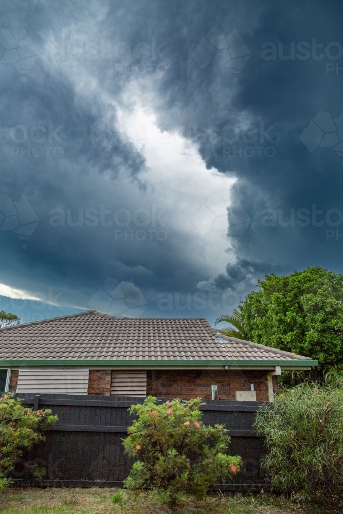 Rain and storm clouds and suburban brick house - Australian Stock Image