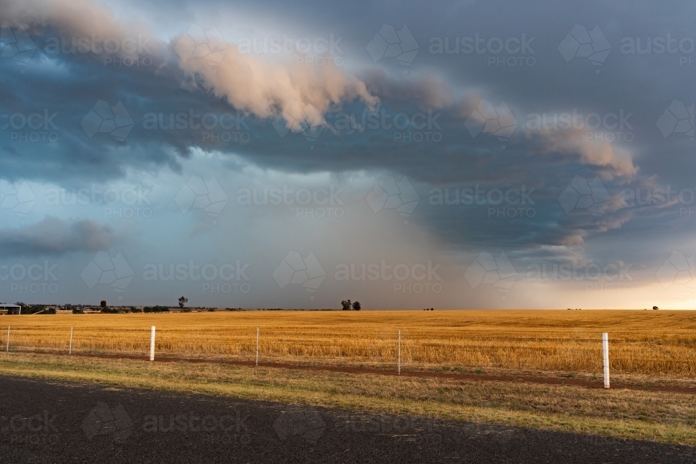 Image of Rain falling from a dramatic stormfront over rural farmland ...