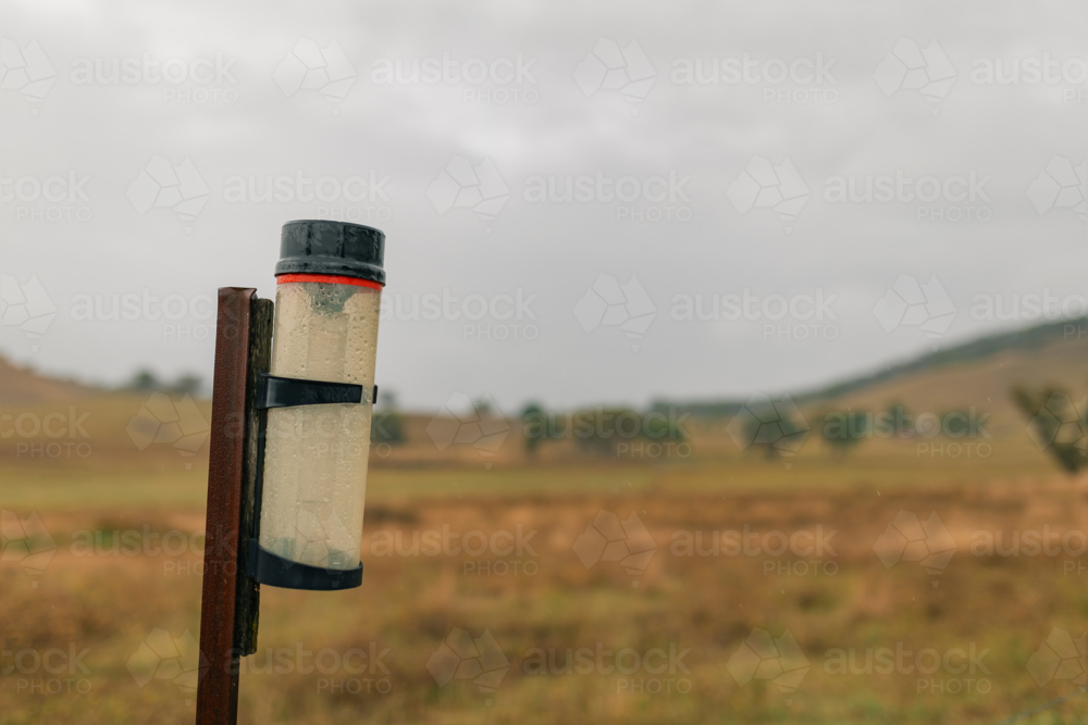 Rain gauge on rural farm property measuring rainfall on stormy day - Australian Stock Image