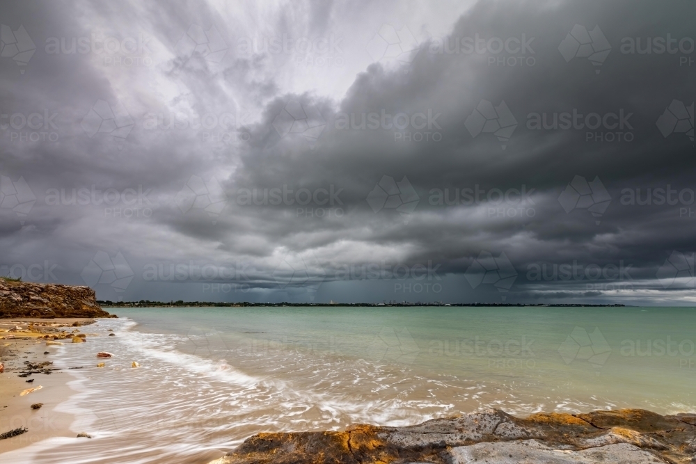 Rain in the distance over Darwin with a dark and stormy sky - Australian Stock Image