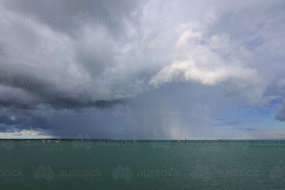 Rain over Darwin Harbour with rainbow - Australian Stock Image